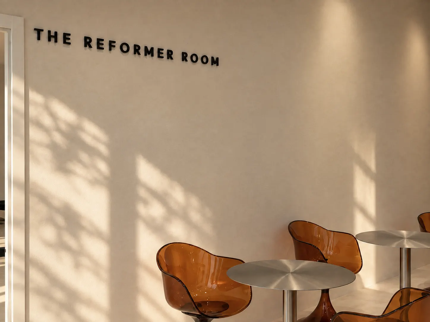 The Reformer Room signage above amber chairs and a chrome table